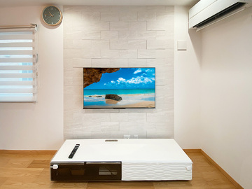 茨城県つくば市でのテレビ壁掛け工事です。エコカラット「ラフクォーツ」が貼られた壁面に壁内補強を施し、コード類を見せない壁内配線でテレビを壁掛け。床上には新しくHDMIコンセントも増設しました。