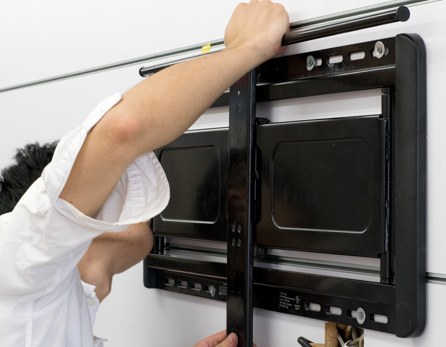 壁掛けテレビの金具を取り付けるスタッフの写真