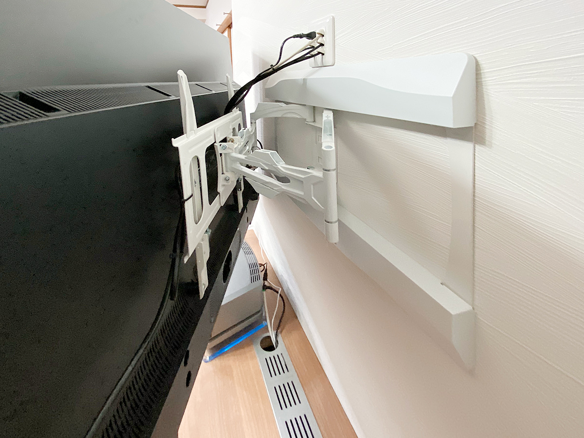 壁掛けテレビの背面の様子。可動式タイプの金具は一旦手前にアームを引き出してから、左右に首を振る構造です。台座上部に作られた専用コンセントにご注目ください。