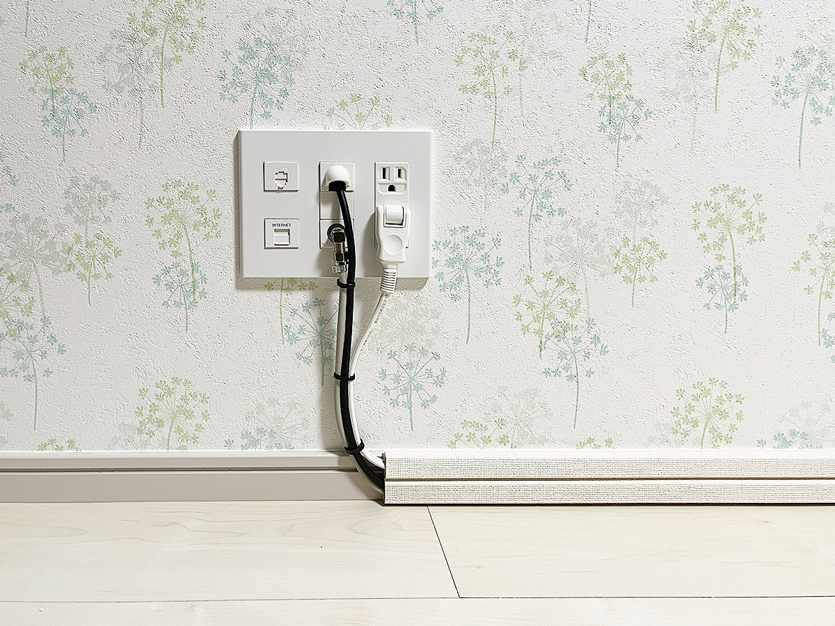 床上の既存コンセント。壁内で上方向にアンテナ線や電源