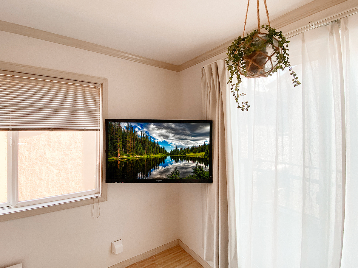 お部屋のコーナースペースを活かした壁掛けテレビ。左右に角度を変えられる可動式金具ならではです。