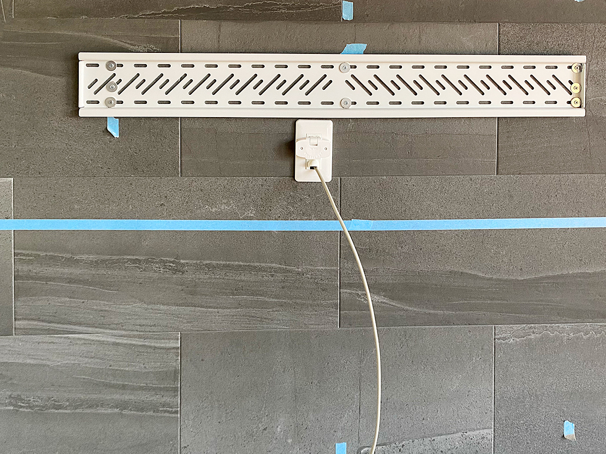 工事中の一枚。エコカラット壁に新しく壁掛けテレビ用のコンセントを作ります。白い線はアンテナケーブルです。