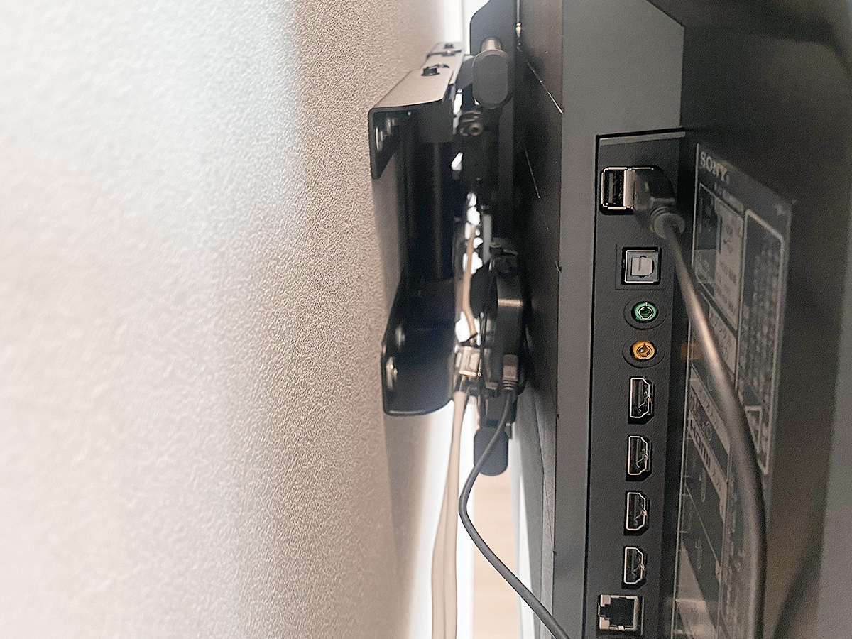 壁掛けテレビの背面の様子。ケーブルを見せないようにしつつ空きスペースを利用して録画用のハードディスクを設置しています。