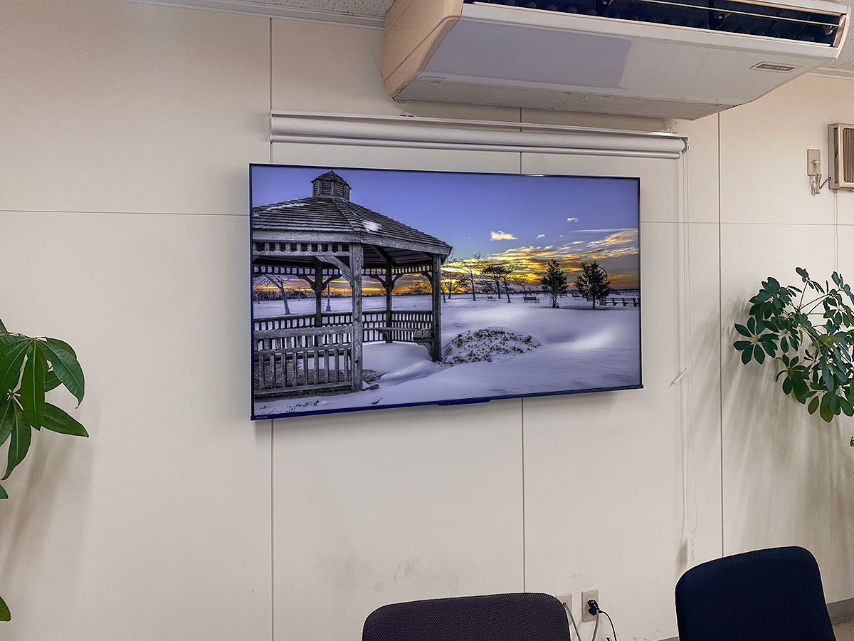 愛知県日進市の企業オフィスの会議室に、壁内補強を施してから65インチのテレビモニターを壁掛けしました。テレビで隠れる場所にコンセントパネルも新設しました。