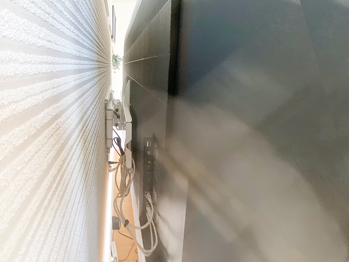 横から覗いてみたところ。今回の施工は以前壁掛けさせていただいたテレビの本体交換。カトー電器が壁内部に補強工事を行い可動式金具を取り付け。壁内配線やテレビ用の専用コンセントパネルも作らせていただきました。自分たちの工事を数年後に改めて見せていただかたちになります。