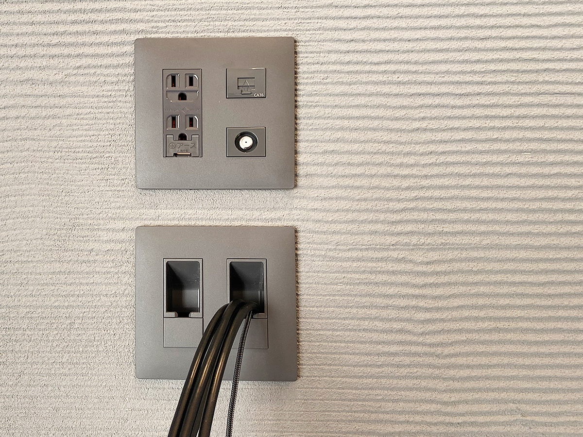 テレビを取り付ける前の専用コンセントの様子。下に見えるのはHDMIケーブルなど。壁内をくぐり棚のコンセントへと向かいます。