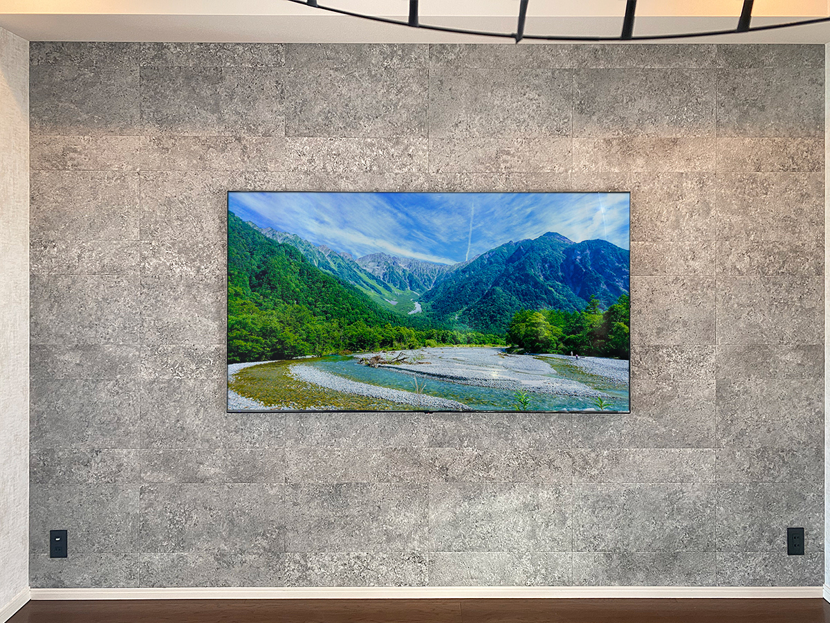 東京都港区のマンションで壁一面にフェイクウォールPIXYを設置し75インチの液晶テレビを埋め込み壁掛け。外装はエコカラット仕上げ。左右にはブラックのコンセントも新設。