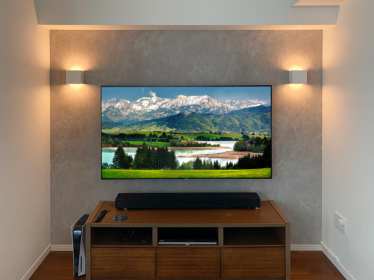 正面から撮影しました。テレビはソニーブラビア KJ-65X8550H。壁掛け時の本体サイズは1450mm×840mm。本体の厚みは52mmという薄さ。左右に間接照明も壁掛けしています。