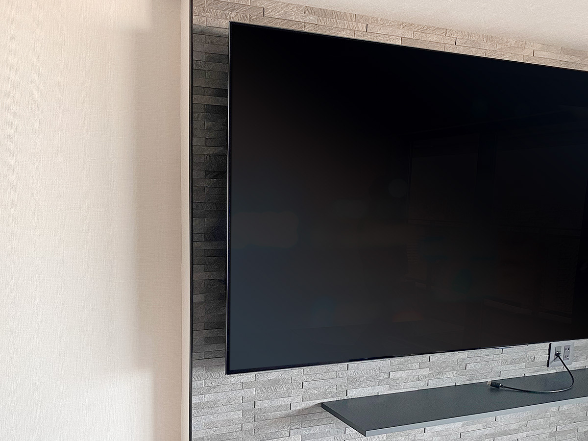 テレビ下にはレコーダー機器やゲーム機の置き場所としてウォールシェルフ（棚）を設置。コンセントも含めダークカラーで統一しています。