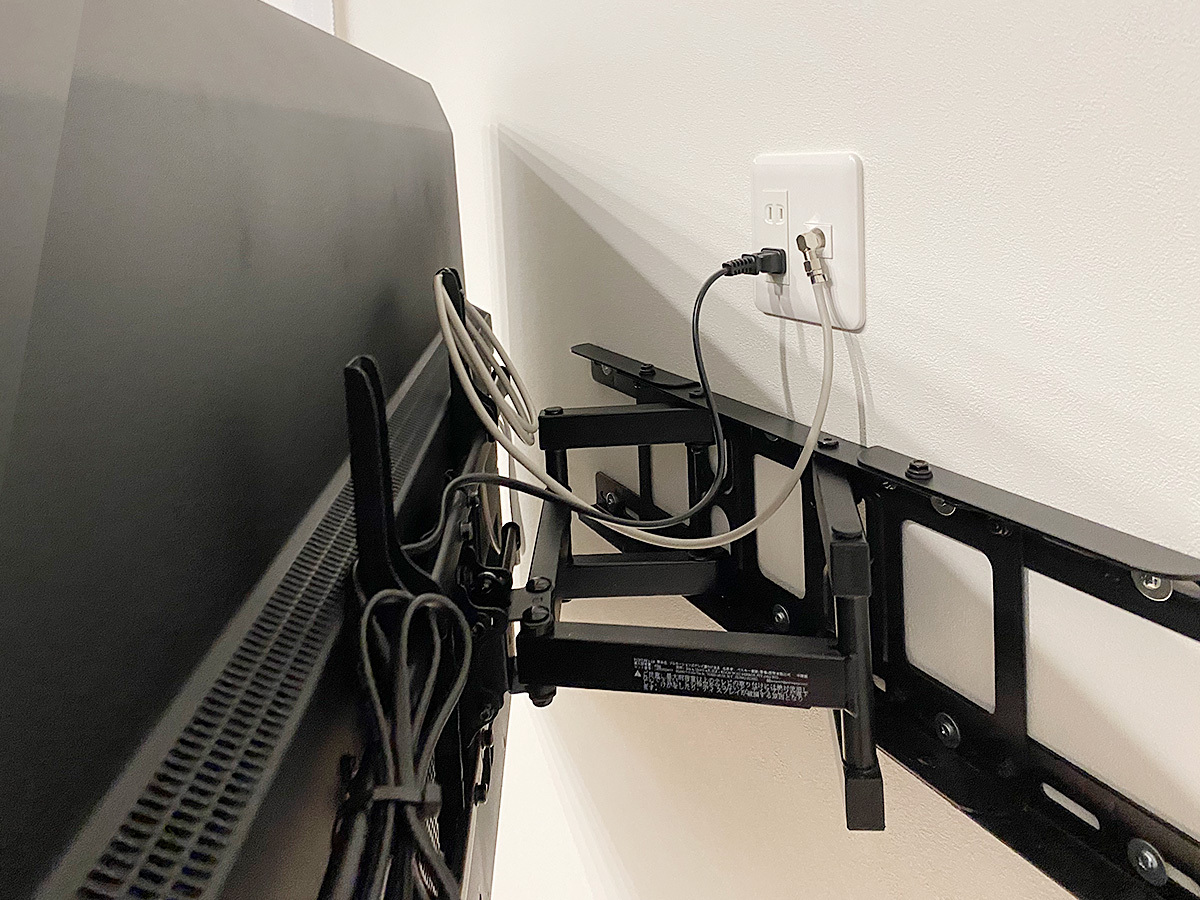 壁掛け金具は手前に引き出し角度を変えられる可動式タイプ。テレビで隠れる位置にはコンセントパネルも新設しました。