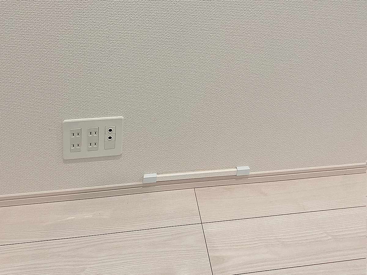 床上コンセント。この右側に柱があるため、一度壁の外に引き出しました。モールと呼ばれる配線カバーで目立たなくしています。