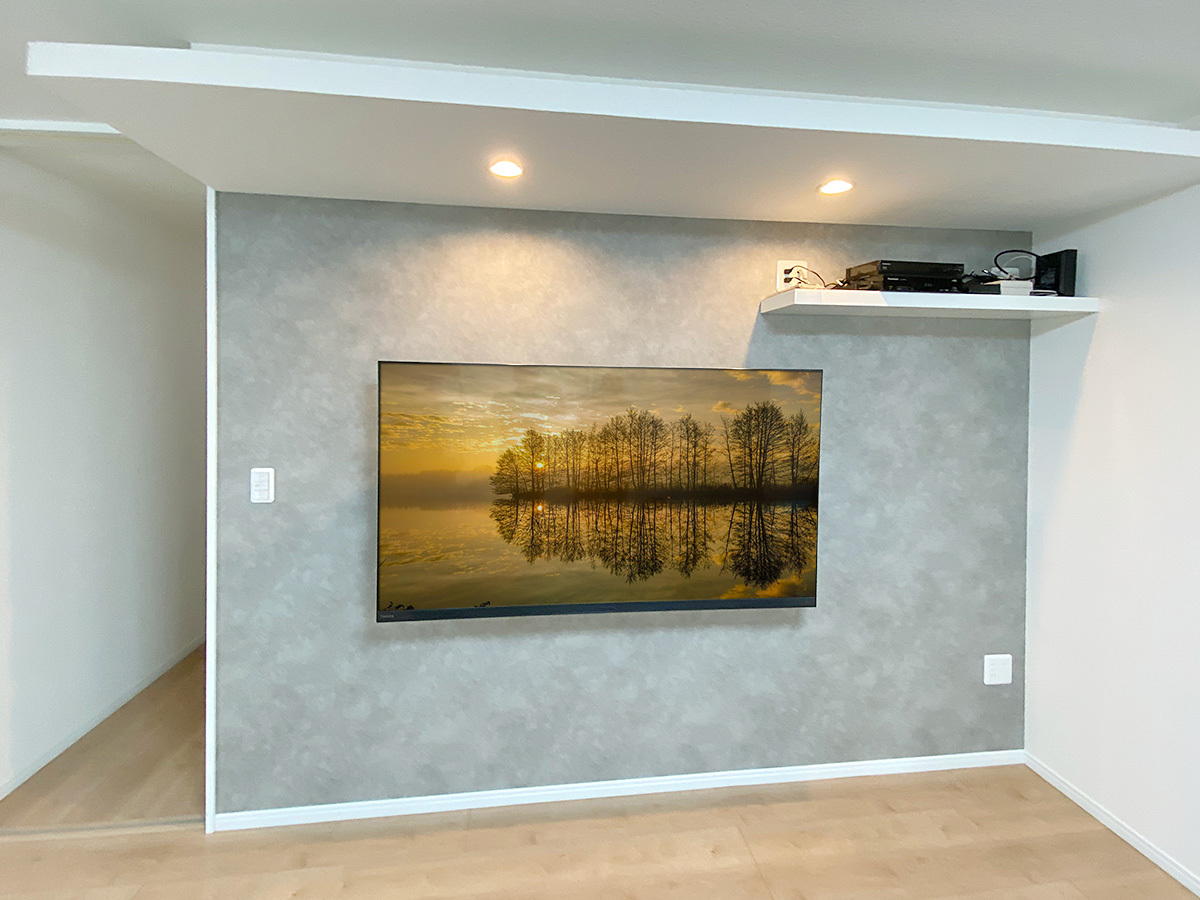 右上の棚のコンセントから壁掛けテレビまでは壁内配線経由でつながっています。ケーブルをなるべく見せないようにするのがカトー電器流。