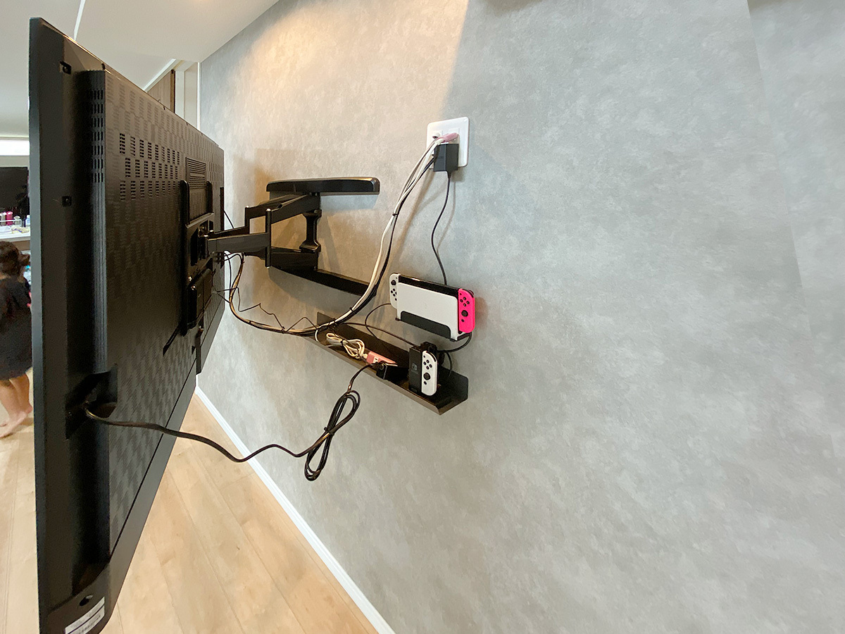 テレビ背面の様子。隙間を生かしてゲーム機などの置き場を作っています。テレビで隠れる位置にコンセントパネルも新設しました。