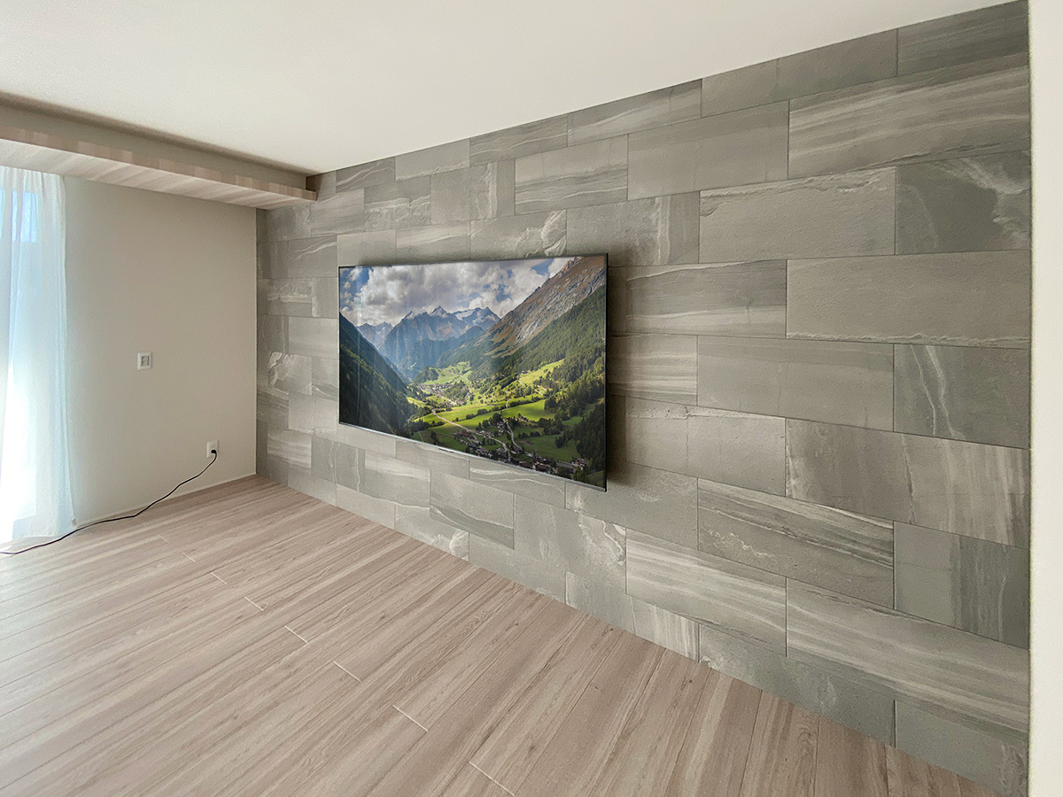 三重県津市での壁掛けテレビ工事。エコカラット「ストーングレース」が貼られた壁面に85型テレビを壁掛け。