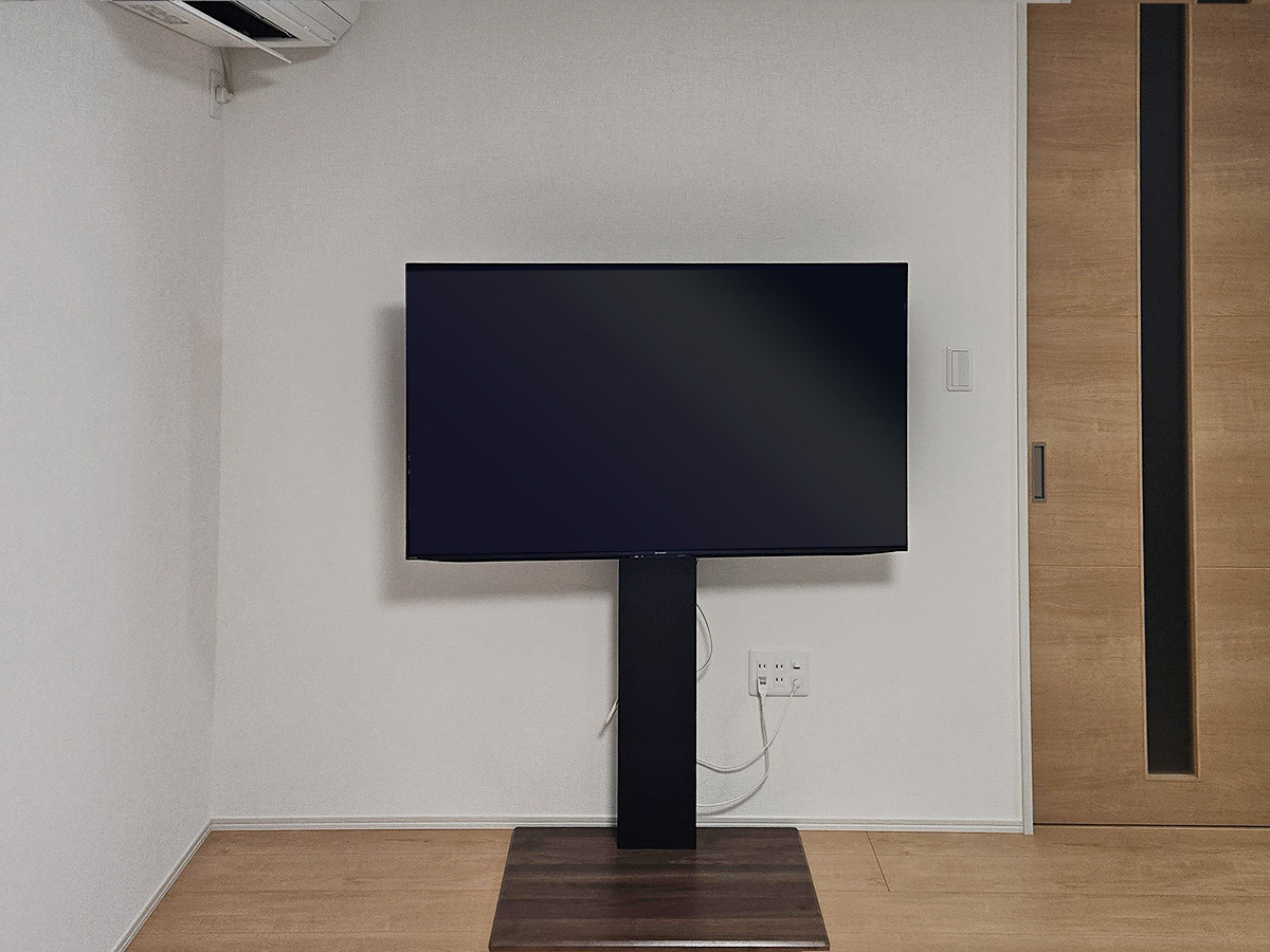 お問い合わせ時にお客様が送ってくださった壁の旧現状写真。壁寄せスタンドをお使いでしたが、台座の厚みやケーブルの隠し方という点では本物の壁掛けに軍配が上がります。