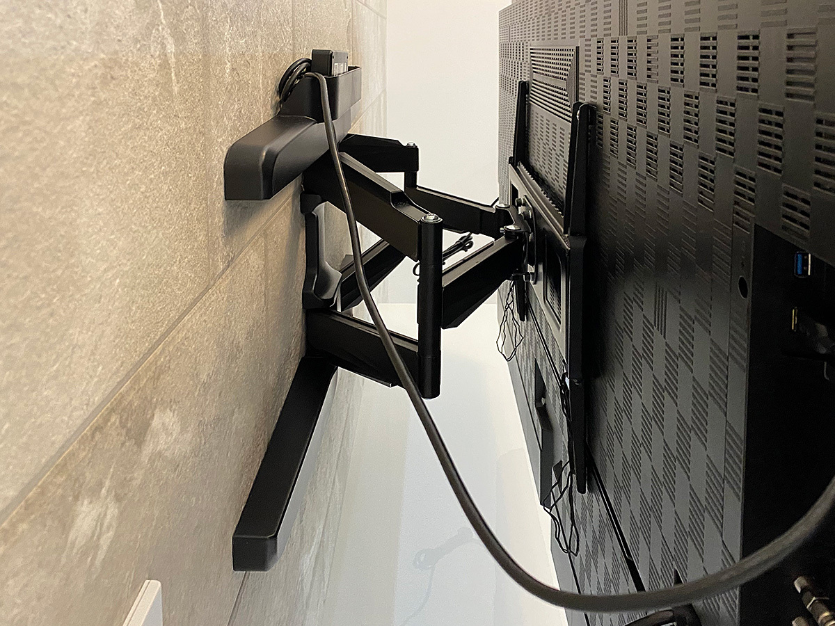 壁掛け金具は角度を変えられる可動式タイプ。台座部が、先に作られた専用コンセントと干渉しないモデルを選びました。