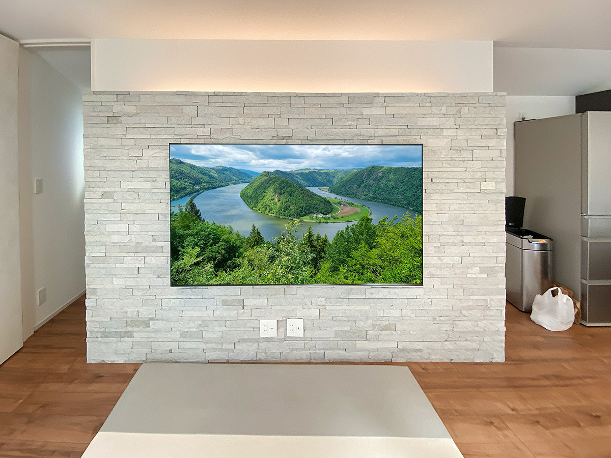 アドヴァン製のタイル壁(ナチュラルロブソンスタック)に75型テレビを壁掛けしてHDMIコンセントを追加