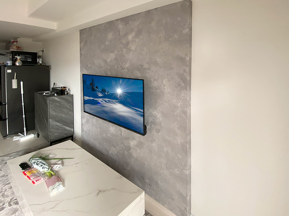 壁掛け金具は薄さを重視した角度固定式タイプを採用。テレビで隠れる位置にコンセントも新設しました。