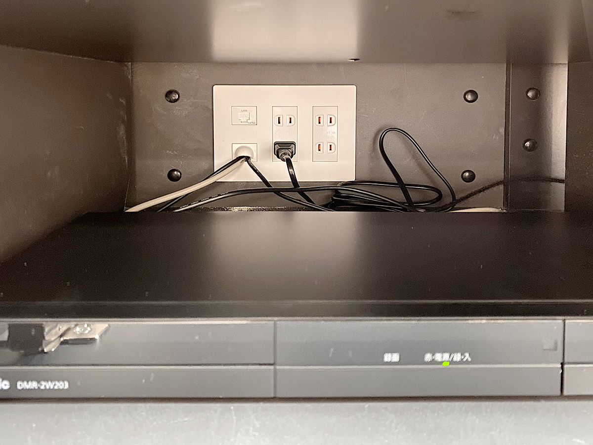 パモウナのテレビボード内部。奥に見えるのが壁掛けテレビへとつながるコンセント。壁内を経由してきたアンテナ線やHDMIケーブルが確認できます。
