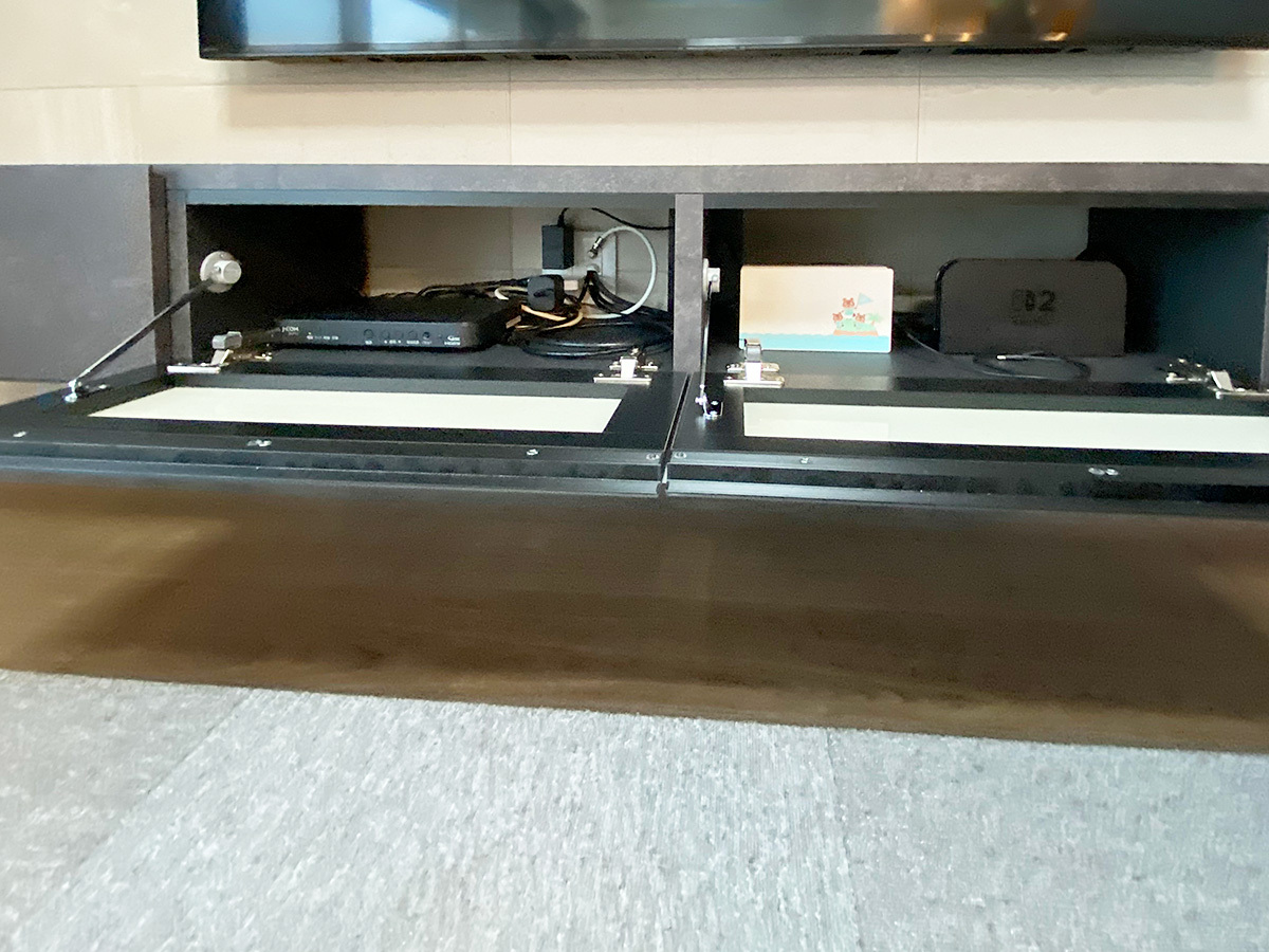 パモウナのテレビボードも壁掛けしました。扉を開くと中にゲーム機などが収納されています。奥のエコカラットに新設されたコンセントパネルにご注目ください。