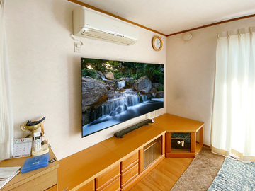 ■電気屋なのでテレビも販売しています
カトー電器商会ではテレビの直接販売も承っております。主な機種はソニーのブラビアシリーとシャープのアクオスシリーズ。壁掛け工事とセットでの購入が可能です。(壁掛け工事とセットの場合特別お値引きが適用されます！)ご注文をいただいたら壁掛け工事当日にテレビも一緒にお運びし、開梱、組み立て、壁掛け、各種設定まで行い、かさばる段ボールや発泡スチロールまで回収いたします。
最新のテレビがその日のうちにやって来て、壁掛けされて、設定まで出来ている…という「テレビ同時購入サービス」。壁掛けを機会にテレビの買い替えを検討されている方にとても人気です。

■愛知県西尾市での壁掛け工事
今回ご紹介するのは愛知県西尾市のお客様。ソニーの75インチ大型液晶テレビ「KJ-75X80K」をご購入いただき壁掛けさせていただきました。お客様は一度弊社のショールームにご来店くださり、そこで細かな内容についてご相談。ゲーム機や録画機器、サウンドバーなどテレビと接続される機材が多く、配線ルートをどのようにするかがポイントとなりました。

■施工当日
施工当日はスタッフ2名が西尾市へ。お客様宅は戸建て住宅。ハウスメーカーはトヨタホーム様です。壁面は石膏ボード＋クロス壁紙。テレビを支える強度がありませんのでカトー電器が得意としている壁内部分補強と間柱を使って強度をしっかり確保。テレビで隠れる位置に新しく専用のコンセントを用意し、各種ケーブルを壁内に通していきます。
H100ボルトのアンテナ線はもちろん、テレビのアンテナ線、DMIケーブルや光デジタルケーブル、そしてLANケーブルまで壁内に通し、テレビ下からコードが見えないようにするのがカトー電器流。
壁内配線の準備まで出来たら金具の設置に取り掛かります。今回使用したのは出幅を抑えた角度固定式きタイプ。その上に75インチの大型テレビを慎重に壁掛け。ガチッと固定し各種ケーブル類を手際よく接続。初期設定、番組設定、インターネット設定など終えたら工事は完了です。
写真のように壁面を有効に利用した大型のシアター空間が誕生しました。

■各部の写真と見どころポイント解説
これより以下、各部の写真と見どころポイントの解説です。

thumbnail.php?id=1506_10_0e569e5452.jpg&alt=愛知県西尾市で同時購入していただいた75インチテレビを壁掛け。各種ケーブルは壁内配線経由で接続しています。
(↑)愛知県西尾市にて、同時購入していただいた75インチテレビを壁掛けしました。アンテナ線やHDMIなどの各種ケーブルは壁内配線経由で接続しておりコード類が見えないのがポイントです。

thumbnail.php?id=1506_11_f12fde9f5b.jpg&alt=テレビはソニーブラビア KJ-75X80K。75インチの大画面液晶テレビです。
(↑)テレビはソニーブラビア KJ-75X80K。75インチの大画面液晶テレビです。壁掛け時の本体サイズは横幅が1675mm、高さが962mm。テレビ本体の厚みは73mm。重量は30kgを超えるため壁掛け時にはしっかりとした下地補強が欠かせません。

thumbnail.php?id=1506_12_a60430a4fe.jpg&alt=カトー電器が壁内に補強工事を施し、金具とテレビを壁掛けしています。
(↑)レコーダー機器やゲーム機などテレビと接続される機器が多い場合は、テレビボードをを併用されるのも一案です。この場合テレビボード側にも壁内経由でテレビとつながる専用コンセントを新設します。

thumbnail.php?id=1506_13_22178dab9e.jpg&alt=お客様はサウンドバーをお持ちで、今回はテレビボード上に置いて使われることに。壁掛けを機にテレビボードを無くしたい方にはサウンドバーも壁掛けする方法などご提案(↑)お客様はサウンドバーもお持ちでした。今回はテレビボード上に置いて使われることに。壁掛けを機にテレビボードを無くしたい方にはサウンドバーも壁掛けする方法などをご提案いたします。

thumbnail.php?id=1506_14_d835a29025.jpg&alt=テレビボードに合わせて用意されていた既存コンセント。ここからアンテナ線と100ボルトの電源を壁内で分岐・延長し壁掛けテレビに利用しました。
(↑)テレビボードに合わせて用意されていた既存コンセント。ここからアンテナ線と100ボルトの電源を壁内で分岐・延長し、壁掛けテレビに利用しました。

thumbnail.php?id=1506_15_d82be2bd21.jpg&alt=壁掛け金具はテレビの出幅を抑えてくれる角度固定sきタイプを採用。
(↑)壁掛け金具はテレビの出幅を抑えてくれる角度固定sきタイプを採用。

thumbnail.php?id=1506_16_2a2c21d62f.jpg&alt=こちらは録画機器。の「NASNE(ナスネ)」。録画したテレビ番組をスマホで視聴できる便利なレコーダー機器です。
(↑)こちらは録画機器。の「NASNE(ナスネ)」。録画したテレビ番組をスマホで視聴できる便利なレコーダー機器です。

■接続機器が多くても大丈夫
壁掛けテレビでは、テレビのみならず録画機器やゲーム機、サウンドバーやAVアンプなどの配置や配線も考えなければいけません。
「テレビにつながっている機材、我が家はこれだけあるんですけど…きれいにまとまりますか？」
お問い合わせの時点でこのような質問をたくさんいただきますがご安心ください。カトー電器では壁内配線を中心とした各種機器の配線、置き場所についてさまざまなタイププランをご提案しております。
ホームページの「無料壁掛け診断」で今現在お使いの各種機器をお伝えくだされば、経験豊富な施工チームがお客様の現状に合った最適プランをいくつかご提案させていただきます。
