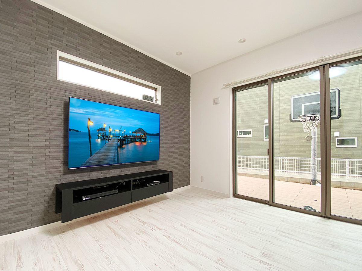 エコカラットのグラナスルドラが貼られた壁面にカトー電器オリジナルのフロートテレビボードと65インチ液晶テレビとの組み合わせです