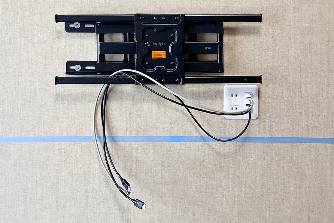 テレビうしろの壁面に専用のコンセントパネルを新設した例。青いマスキングテーブルはテレビの取り付け位置を表しています。