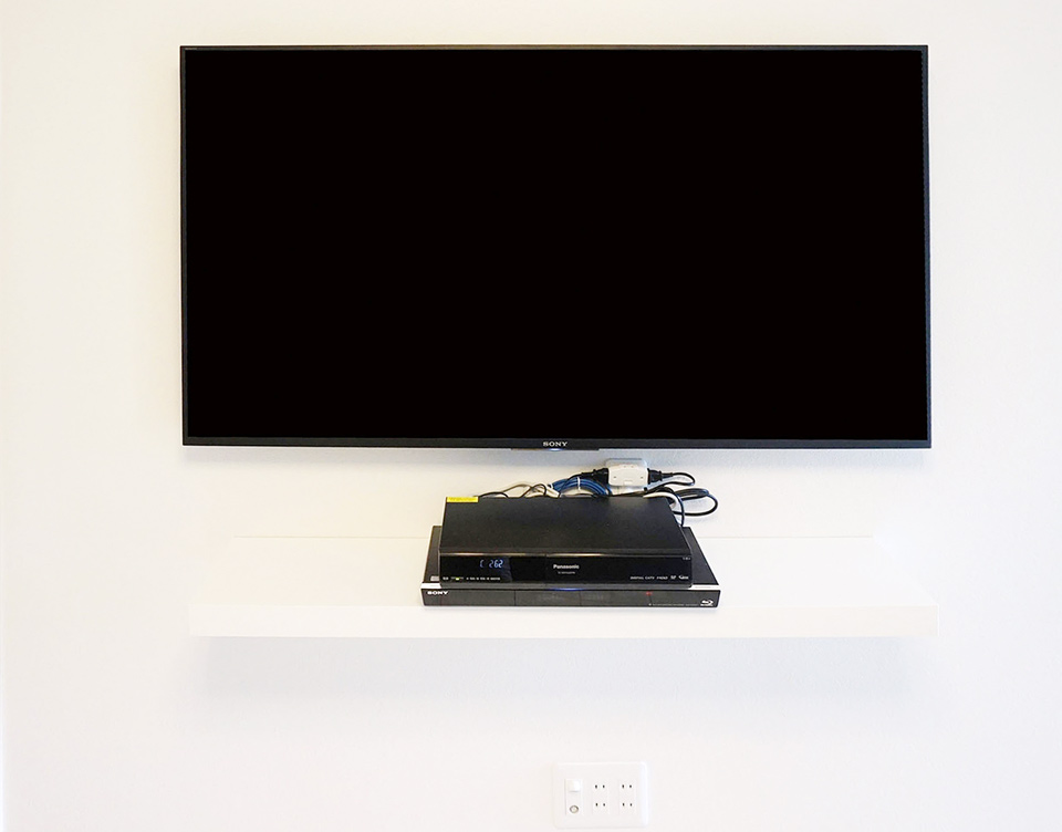 こちらは壁掛けテレビの下に棚を設置した例。テレビとレコーダーを直結せず、壁内で繋いでいます。 